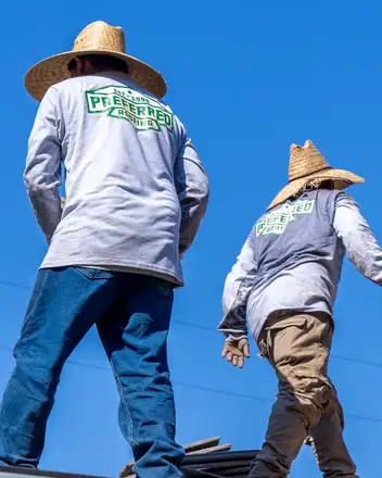 Two Preferred Roofing crew members walking a roof