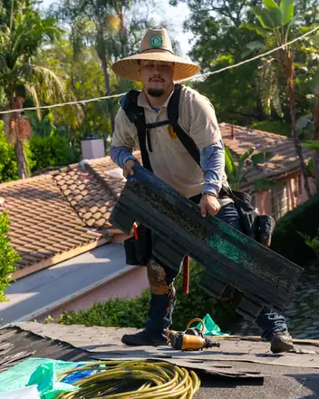 Crew member carrying shingles on a roof